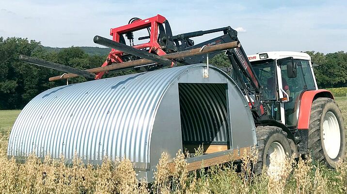Un tracteur portant une cabane en acier galvanisé