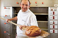 Boulanger avec un pain sur sa pêle en bois