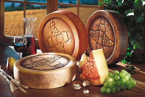 trois fromages entiers et un verre de vin sur une table