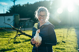 Une femme tient un poulet blanc dans ses bras.