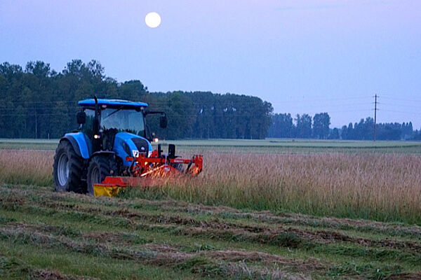 Traktor mit Frontmähwerk beim Mähen der Spenderwiese