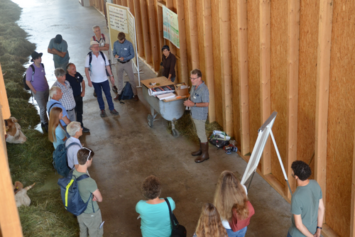 Eine Gruppe Menschen in einem Stall bei einem Vortrag 