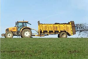 Tracteur et épandeuse à fumier au travail sur un champ.