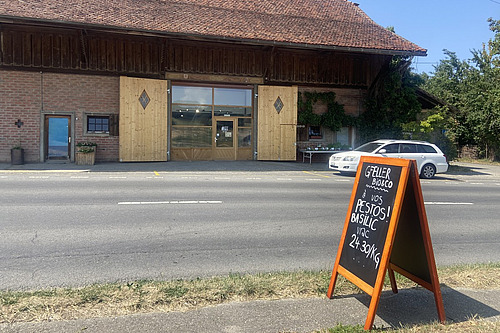 Une maison et une rue, avec un panneau d'information devant.