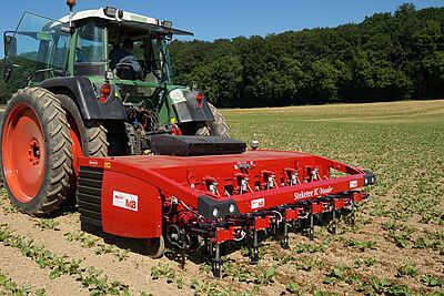 Un tracteur avec une sarcleuse rouge