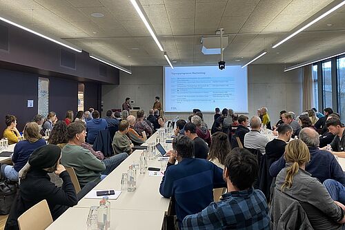 Une salle pleine avec une présentation Powerpoint.