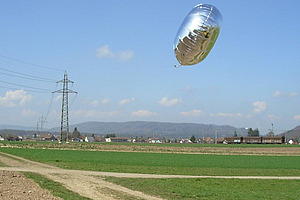 Un ballon en aluminium argenté au-dessus d'un champ de maïs.