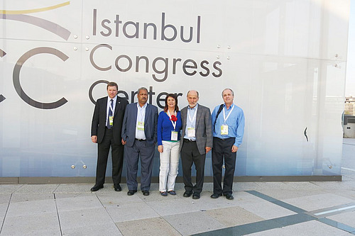 Otto Schmid se tient devant le centre des congrès d'Istanbul, entouré d'un groupe de personnes.
