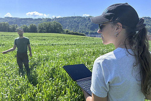 un chercheur et une chercheuse avec ordi dans les parcelles d'essai