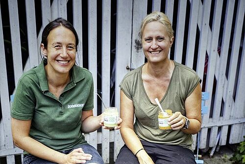 Deux femmes tiennent des pots de houmous.