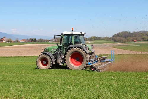 Vu de côté: tracteur tirant une houe rotative dans un champ.