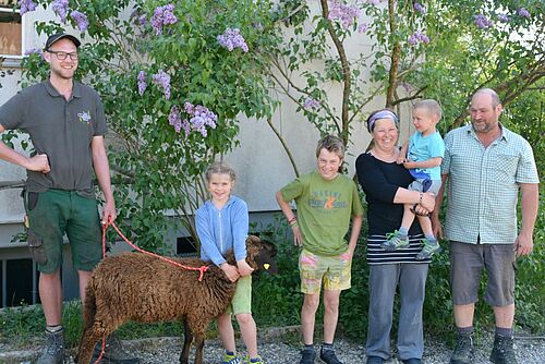 Groupe des personnes avec un mouton devant une maison