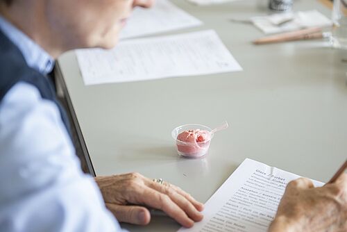 Une personne remplit un questionnaire, à côté duquel se trouve un gobelet contenant une boule de glace. 