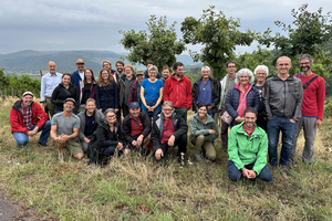 Un groupe de personnes devant des vignes avec des arbres.  