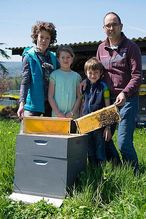 Un homme, une femme et deux enfants derrière une ruche