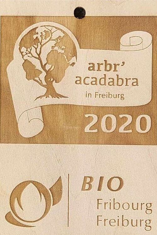 Une plaquette en bois avec le logo du projet et de Bio Fribourg