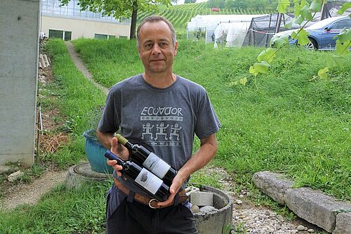 Andreas Tuchschmid avec deux bouteilles de vin