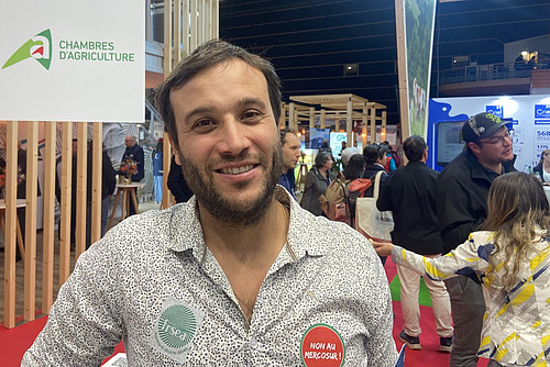 Ein Mann posiert mit einem gesprenkelten Hemd an einer Landwirtschaftsmesse. 