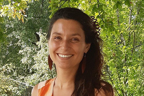Portrait d'une femme aux longs cheveux bruns sur fond vert.