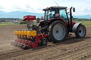 Tracteur et semoir dans un champ fraîchement travaillé.