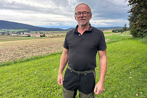 Ein Mann mit Kurzarm-Shirt vor einem offenen Feld.