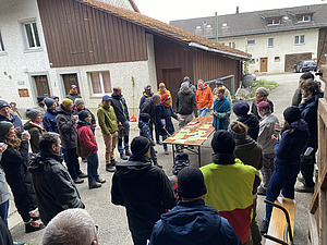 Un groupe se tient autour d'une table dans une cour et discute.