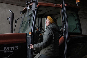 Une femme monte dans un tracteur.