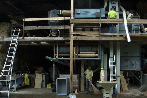 Intérieur d'un moulin artisanal, avec des installations techniques sur deux étages.