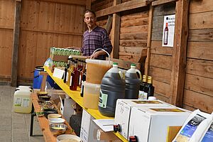 un homme avec un stand rempli de denrées alimentaires, dont certaines en gros emballages.