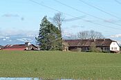 Deux bâtiments à l'arrière plan; une prairie au premier plan.