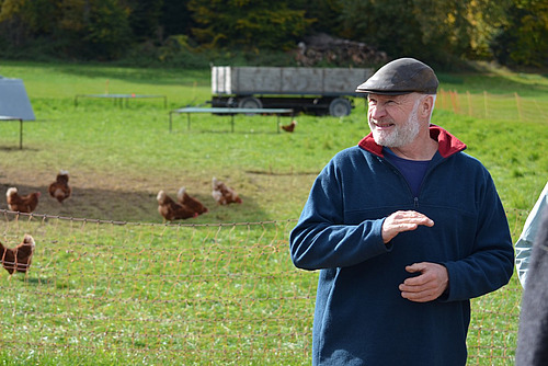 L'agriculteur se tient devant un enclos extérieur pour volailles.  