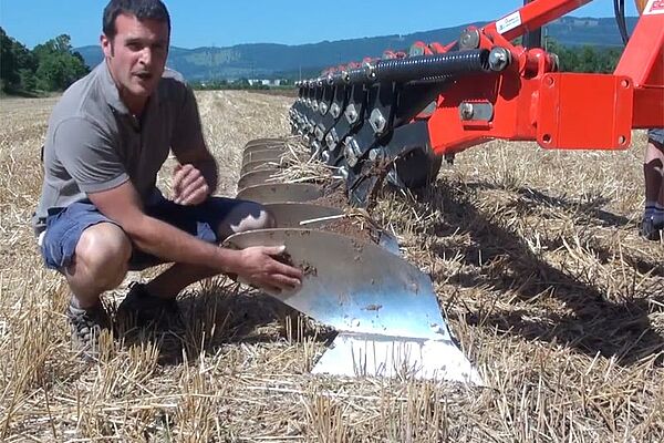 Berater kauert neben dem Schälpflug und erklärt die Funktionsweise