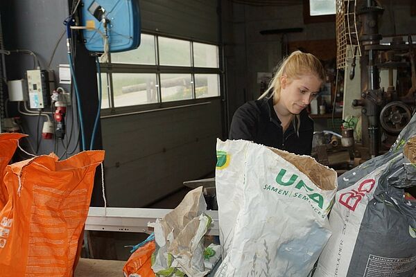 Une femme dans un atelier, au premier plan des sacs en papier.