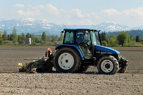 Un tracteur bleu se trouve dans un champ.