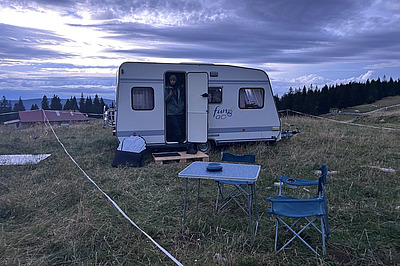 Wohnwagen mit Tisch und Stuhl davor in der Abenddämmerung.