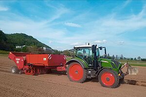 Tracteur avec remorque rouge pendant la plantation