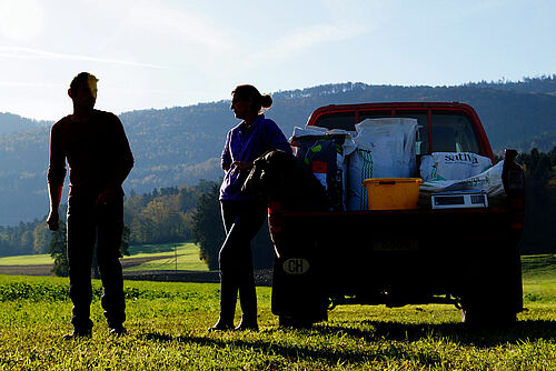 Paysan et paysanne au champ à côté d'un auto