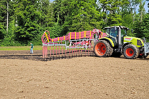 Un tracteur équipé d'un tuyau traînant épand du charbon végétal avec du lisier sur le champ d'essai.