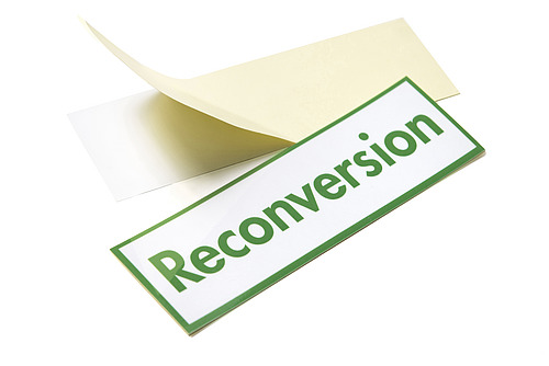 Etiquette avec fond blanc et écriture en vert. Le texte est le mot suivant: "Reconversion". 