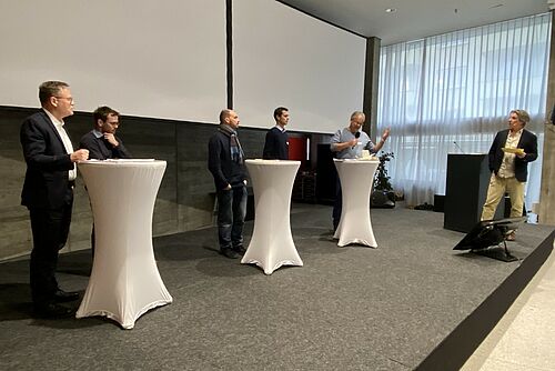 Six hommes sur un podium.