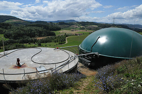 Installation de biogaz sune ferme, avec à gauche le ballon sous lequel le gaz se trouve. En arrière-plan, une belle nature.
