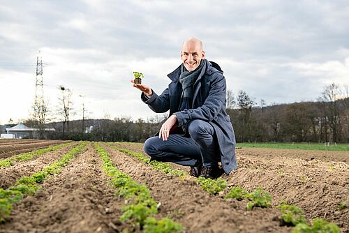 Le directeur de Bio Suisse tenant une plante dans sa main sur le champs.