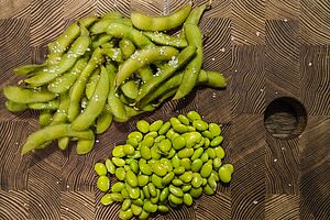 Petit tas de gousses vertes à côté d'un petit tas de grains verts.