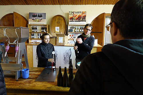 Deux personnes se tiennent à une table sur laquelle sont disposées des bouteilles de champagne.