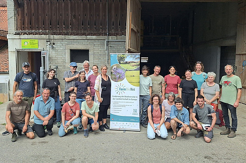 Un groupe de personnes d'âge mûr se tient en rang. Au milieu d'eux se trouve une banderole du projet FarmBioNet.