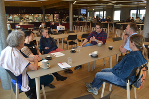 Plusieurs personnes s’assoient autour d’une table et gesticulent.