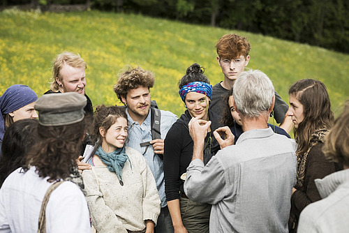 Eine Gruppe von Schüler*innen erhält vom Lehrer Informationen zu einem Gras.