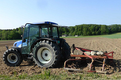 Vieille machine rouge derrière un tracteur.