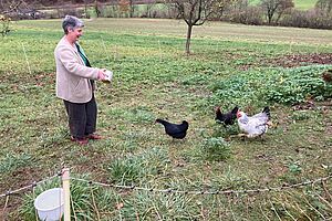 La protagoniste donne à manger aux poules dans un pré