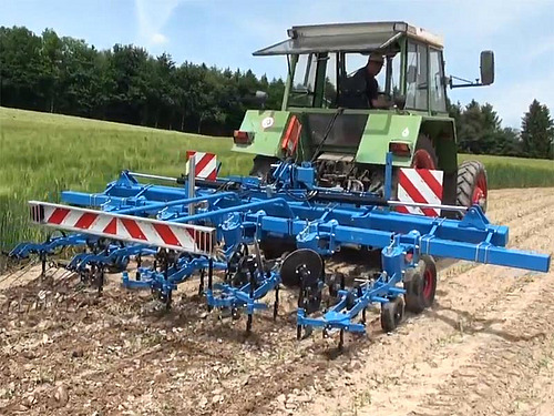 Tracteur et sarcleuse en train de sarcler un très jeune maïs.
Vue aérienne de la 2ème journée nationale des grandes cultures bio.
Portrait de Philippe Tavel.
Portrait de Bernard et Thierry Candaux
Des visiteurs se penchent sur le sol fraîchement